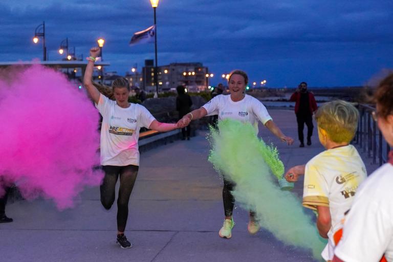 People running and getting covered in powdered paint during a colour run!
