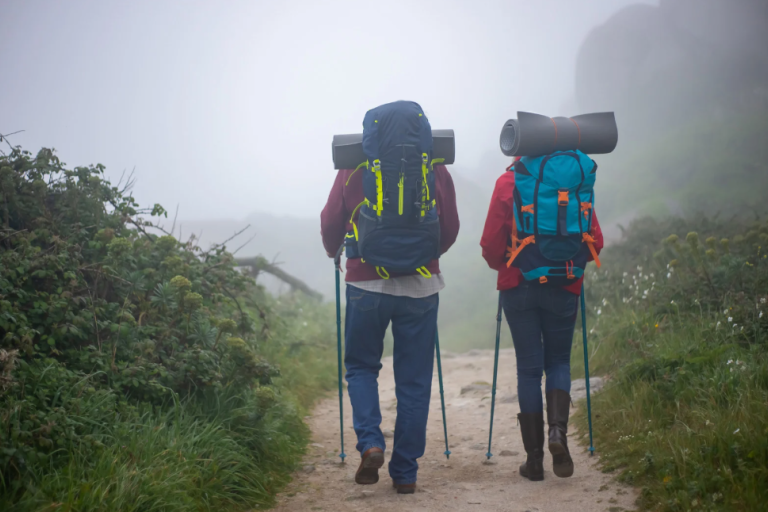 Two people trekking with walking poles on a path on a cloudy day