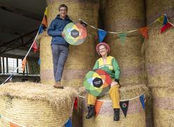 a man and woman sitting on hay bales holding colourful Culture Night signs
